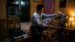 Seorang anak mendampingi ibunya yang duduk di kursi roda setelah meninggalkan karier untuk merawatnya.